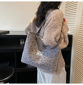 Close-up of gray corduroy tote bag with black heart and bow patterns in a lifestyle setting