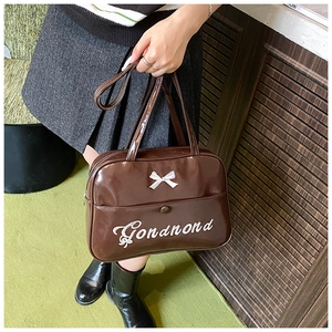 Detail of dark brown glossy tote bag with white bow and Gondnond embroidery