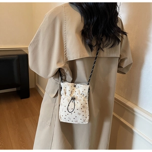 Detail of white corduroy crossbody bag featuring brown heart prints and drawstring closure