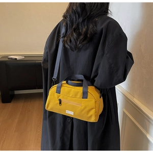 Detail of yellow nylon crossbody bag with JL FASHION label on a lifestyle model background