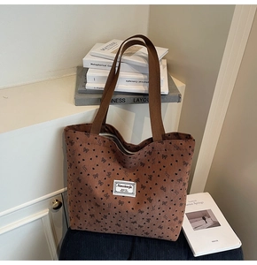 Detail of brown corduroy tote bag featuring black heart patterns and fabric handle