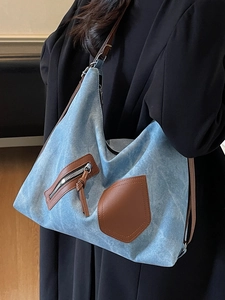 Blue denim hobo shoulder bag with brown leather details shown from a side perspective