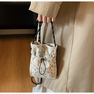 Close-up of pleated corduroy phone bag featuring heart patterns and drawstring closure