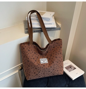 Detail of brown corduroy tote bag with black heart and bow prints on blue chair