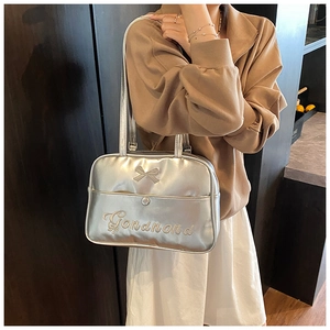 Detail of silver metallic PU tote bag featuring embossed bow and Gonanond embroidery