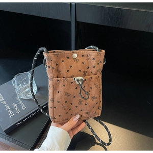 Detailed texture of brown corduroy phone bag featuring black heart bow prints and strap