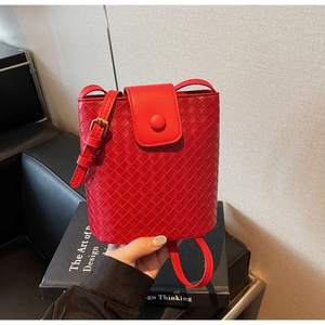Detail of red woven texture bucket bag featuring metal buckle and adjustable strap