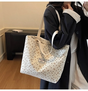 Detail of corduroy tote bag featuring heart and bow patterns on a shoulder strap