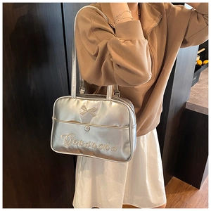 Close-up of metallic silver tote bag featuring a bow relief and embroidered logo detail