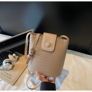 Detail of light beige woven bucket bag with magnetic clasp and adjustable strap