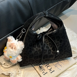 Leopard print pillow handbag with knot handle and plush bear pendant in a stylish setting