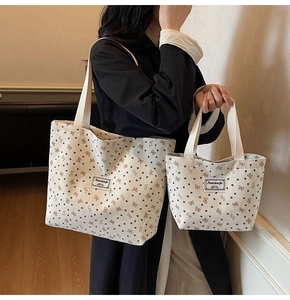 Detail of off-white corduroy tote bag set with black heart and bow prints on model
