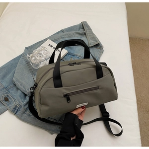 Detail view of olive green nylon bag with dual zippers and front zip pocket on white bedding
