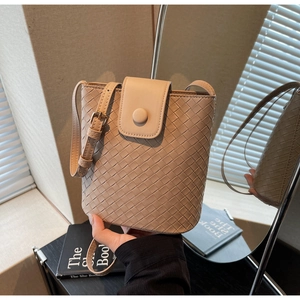 Detailed close-up of beige woven bucket bag with smooth leather texture and crossbody strap