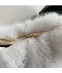 Détail d'une fermeture éclair en métal doré clair sur un sac en fausse fourrure blanche