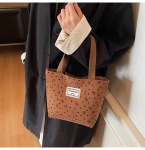 Close-up of brown corduroy tote bag with rabbit patterns and fabric logo label