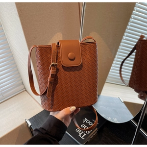 Close-up of brown woven bucket bag with detailed texture and adjustable shoulder strap