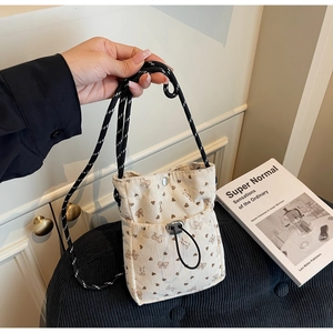 Detail of cream corduroy crossbody bag featuring brown heart and bow print patterns