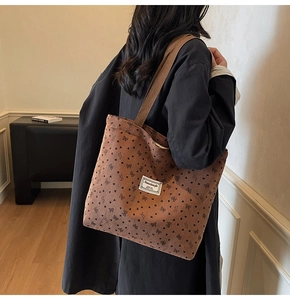 Detail of dark brown corduroy tote bag with heart patterns and sturdy shoulder straps