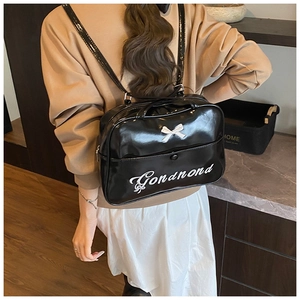 Close-up of black patent leather backpack with white bow and Gonanond lettering detail