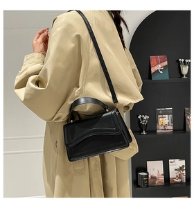 Detail of the elegant black square bag with wave-edge flap and golden metal hardware