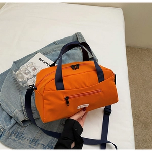 Detail of bright orange nylon crossbody bag with contrast blue handles and white logo tag