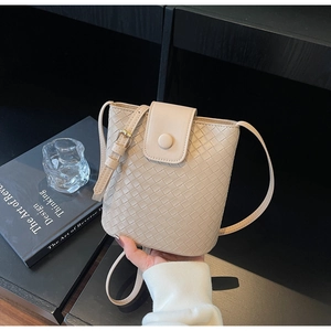 Close-up of beige woven bucket bag showing intricate interlaced leather texture and strap