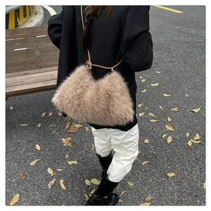 Close-up of a khaki faux fur bucket bag with a leather strap in an autumn street setting