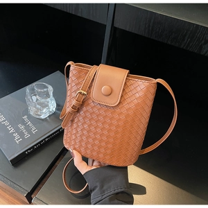 Close-up of the brown woven leather texture and circular buckle on a bucket bag
