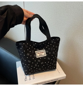 Close-up of black corduroy tote bag with white heart prints and brand label details