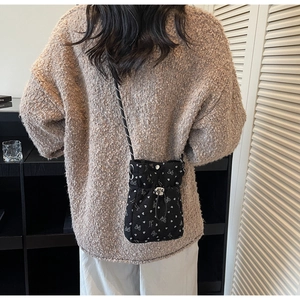 Detail of black corduroy crossbody bag with white heart prints on model shoulder