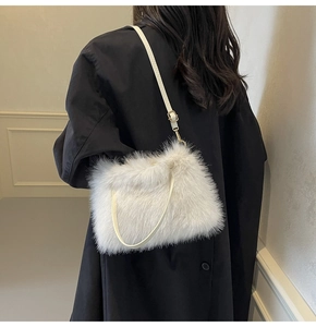 Détail d'un sac à bandoulière en fausse fourrure blanche porté sur un manteau noir élégant