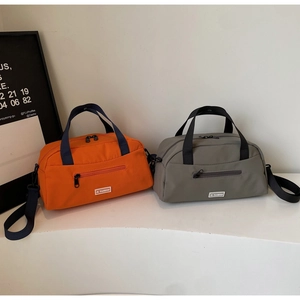 Detail of grey and orange nylon tote bags with JL FASHION logo and front zippers