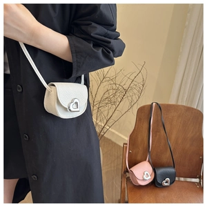 Détail du mini sac selle avec boucle métallique en cœur, disponible en trois coloris