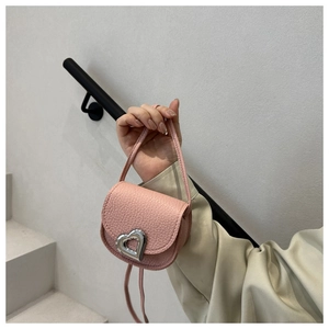 Detail of pink lychee leather handbag featuring a large silver heart-shaped metal buckle