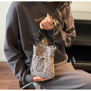 Detail of grey pleated corduroy crossbody bucket bag with black bows and hearts print