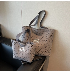Detail showing two sizes of taupe corduroy tote bags with black heart and bow prints