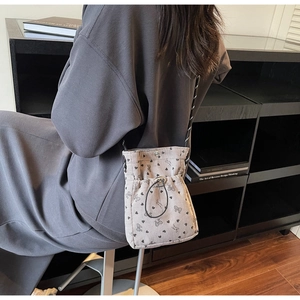 Detail of pleated corduroy phone bag with black heart patterns and drawstring closure