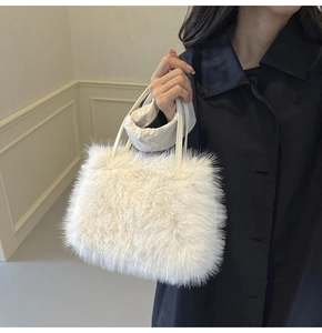 Détail du sac à main en fausse fourrure blanche avec poignées en cuir sur manteau noir