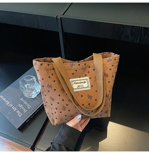 Detail of brown corduroy tote bag featuring heart and bow patterns and soft fabric handles