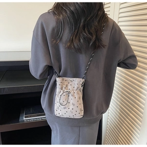 Detail of pleated corduroy crossbody phone bag with heart pattern and woven strap