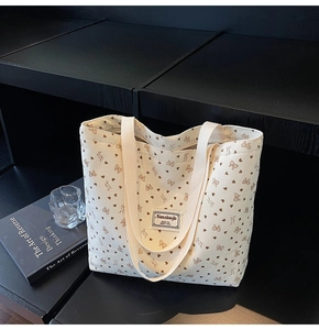 Detail of off-white corduroy tote bag with bow print and sturdy fabric shoulder straps