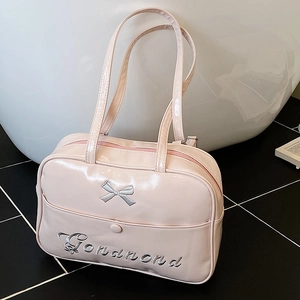 Pink patent leather tote bag with silver bow embroidery and shoulder straps displayed on floor