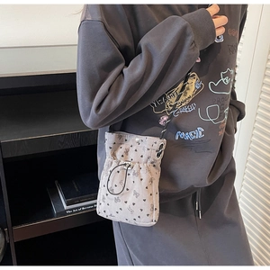 Detail of grey corduroy mini crossbody bag with black heart and bow print and drawstring