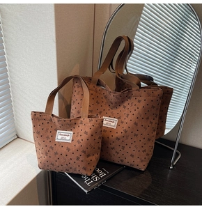 Detail view of brown corduroy tote bags with heart and bow patterns in two sizes
