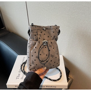 Detail of grey corduroy bucket bag featuring black heart prints and drawstring closure