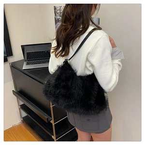 Detail of black faux fur bucket bag with leather strap worn by a model in a stylish room
