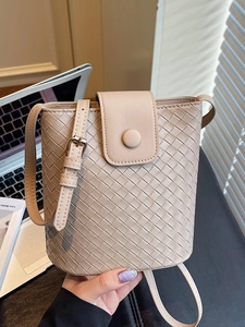 Chic apricot woven leather bucket bag with adjustable strap in natural lighting