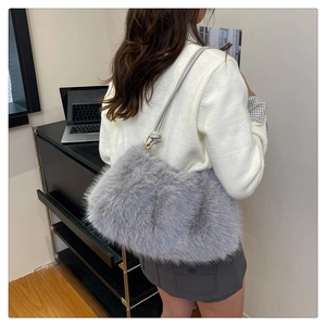 Detail of grey faux fur bucket bag with a slim leather strap in a minimalist office setting