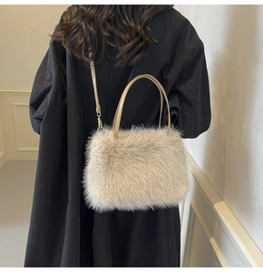Detail of plush faux fur crossbody bag in cream color worn by a model in a black coat